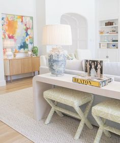 a living room filled with furniture and a white table topped with two yellow stools