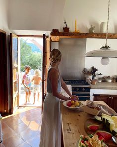 a woman in a white dress standing at a counter with plates of food on it