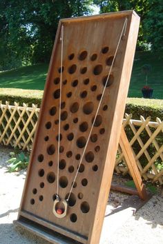 a wooden board with holes and chains attached to the back, sitting in front of a fence