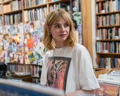 a woman standing in front of a bookshelf with many books on the shelves