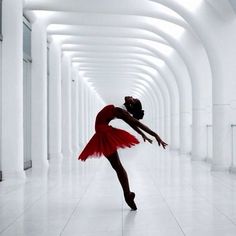 a ballerina in a red tutu is dancing on the white floor with arches