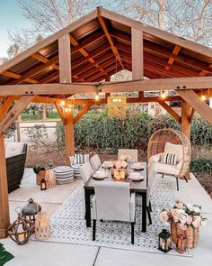 an outdoor dining area with wicker furniture and lights on the ceiling, surrounded by greenery