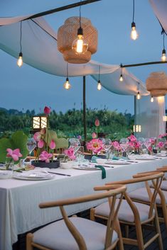 a long table set up with flowers and place settings for an outdoor wedding reception at dusk