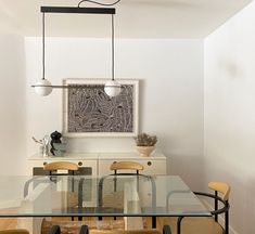 a dining room table with four chairs and an art piece on the wall above it