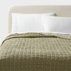 a bed with two pillows on top of it and white sheets in front of the headboard