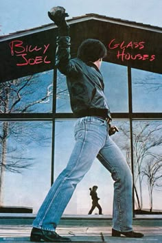 a man in jeans and boots walking past a building with the words billy glass houses written on it