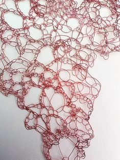 a piece of red string art on a white surface