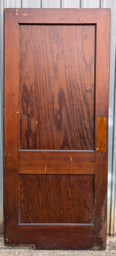 an old wooden door sitting on the side of a building next to a metal wall