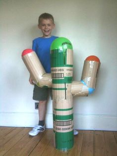 a young boy is standing next to a cardboard character made out of toilet paper rolls