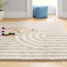 a child's play area with toy train tracks on the floor and potted plant