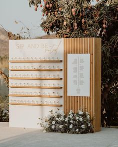 a wooden sign sitting next to a tree filled with flowers