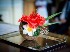 red and white flowers are in a vase on a tray