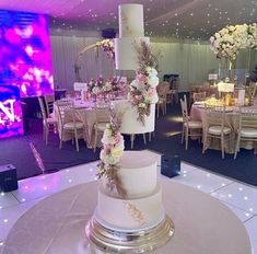 a wedding cake sitting on top of a table in front of a purple and white backdrop