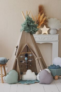 a teepee tent sitting on top of a floor next to pillows and other items