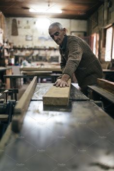 an older man working in a woodworking shop with his hands on a piece of wood