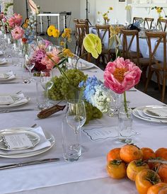 a long table is set with flowers and fruit