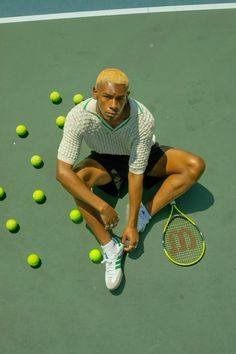 a man sitting on top of a tennis court holding a racquet and ball