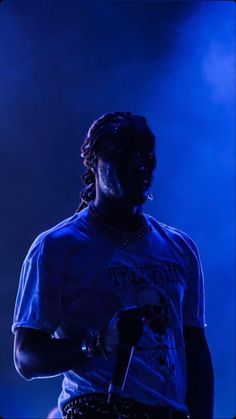 a man with dreadlocks on his head standing in front of a blue light