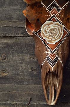 a cow's skull with a rose painted on the side and diamond pattern around it