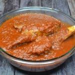 a bowl filled with red sauce on top of a wooden table