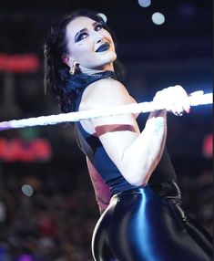 a woman in black and blue outfit holding a white rope with lights on her face