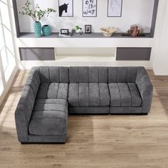 a large gray sectional sofa sitting on top of a hard wood floor