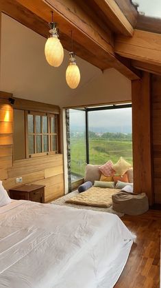 a large bed sitting in a bedroom on top of a wooden floor next to a window