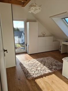 an attic bedroom with hardwood floors and white furniture, windows overlooking the yard area is shown in this image