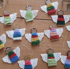 several pieces of fabric are hanging from twine and decorated with tiny angel ornaments on lace doily