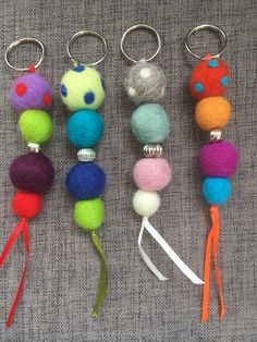 four different colored balls and key chains on a gray cloth with white string attached to them