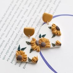 a pair of sunflower earrings sitting on top of a piece of paper