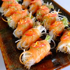 some sushi is sitting on a plate with lettuce and tomato toppings