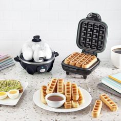 some waffles and eggs are on a table next to an egg cooker