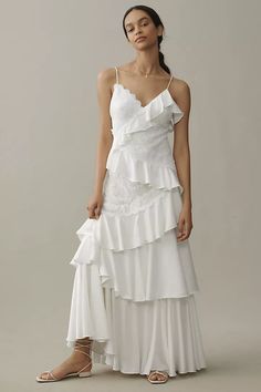 a woman is wearing a white dress with ruffles on the bottom and side