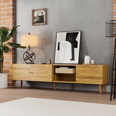 a living room with a large wooden entertainment center in front of a brick wall and potted plant