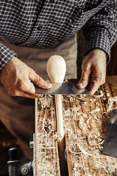 a man is carving an egg with a large wooden block in front of him on a workbench