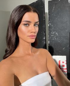 a woman in a white strapless dress posing for the camera with her hand on her hip