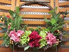 a bunch of flowers sitting on top of a wooden bench next to a wall covered in wood slats