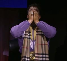 a man covering his eyes while standing on stage