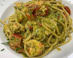 a white plate topped with pasta covered in pesto