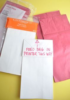 some pink and white envelopes sitting on top of a yellow table next to each other