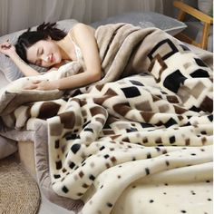 a woman laying on top of a bed covered in a brown and white animal print blanket