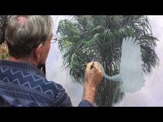 an older man is painting a palm tree