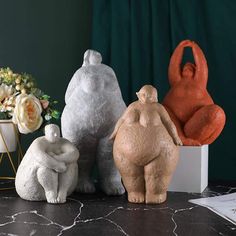 three ceramic animals sitting on top of a table next to a vase with flowers in it