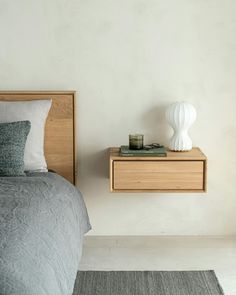 a bedroom with a bed, nightstand and lamp on top of the night stand in front of the bed