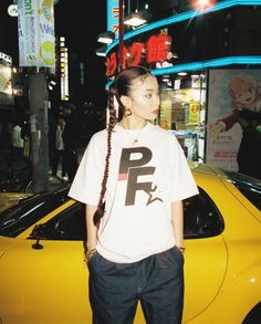 a woman standing in front of a yellow car