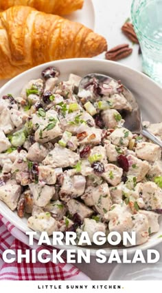 a white bowl filled with chicken salad next to croissants