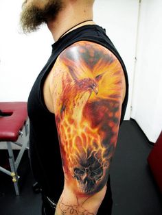 a man with a tattoo on his arm has a flaming bird and skull in flames