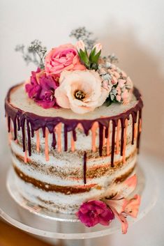 a multi layer cake with flowers and icing drizzled on it