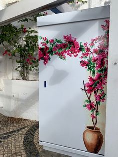 a refrigerator with flowers painted on it in front of a building and stone flooring